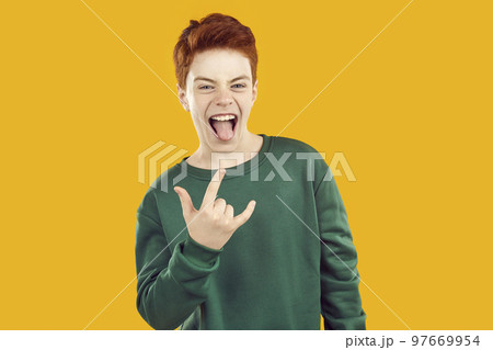 Studio portrait of funny, cheerful, excited child model doing heavy metal gesture 97669954
