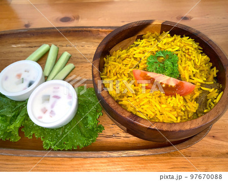 Rice lamb biryani pilaf with lamb or mutton meat and vegetables cucumber  along with yoghurt in a very nice american restaurant 97670088