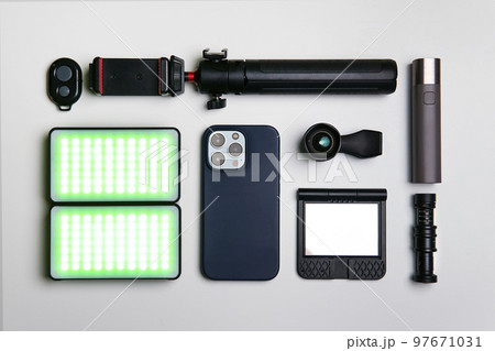 Equipment for shooting video on a smartphone. Microphone, LED lamp, tripod, lens smartphone are on a white table 97671031