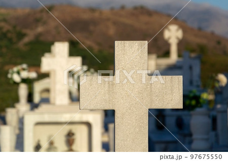 Cross on a grave in a Greek cemetery at dawn 97675550