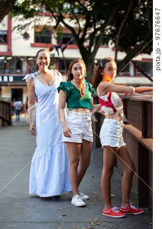 Tourists at one of the bridges along the Cali River Boulevard in the city of Cali in Colombia. Mother and teenager daughters traveling concept. Happy family concept. Tourists at one of the bridges along the Cali River Boulevard in the city of Cali in Colombia. Mother and teenager daughters traveling concept. Happy family concept. 97676647