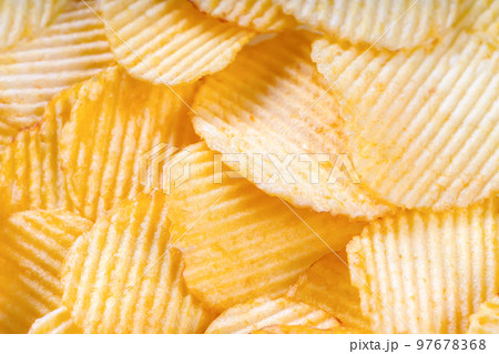 Yellow crispy ridged potato chips close up. Food background 97678368