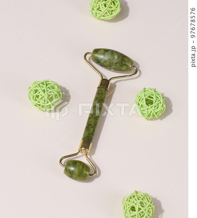 Jade green face massager on a beige background, top view 97678576