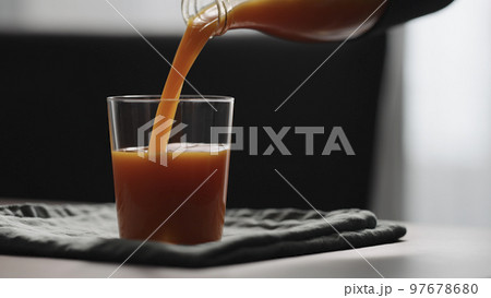 pour carrot juice in tumbler glass on wood table pour carrot juice in tumbler glass on wood table 97678680