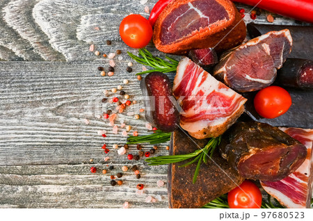 Close up of assorted dry-cured meat on the wooden background Close up of assorted dry-cured meat on the wooden background 97680523