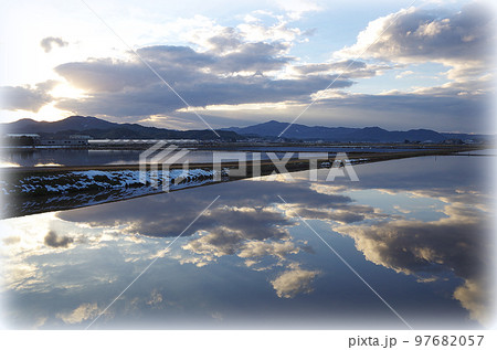 無風の夕方の冬水田んぼが大きな鏡の様に冬の青空と雲を映している構図(イラスト風) 無風の夕方の冬水田んぼが大きな鏡の様に冬の青空と雲を映している構図(イラスト風) 97682057