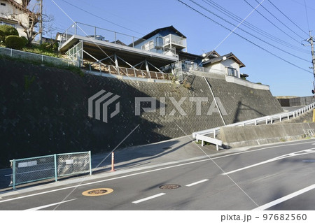 道路沿いの高い擁壁のある住宅団地の入り口 97682560