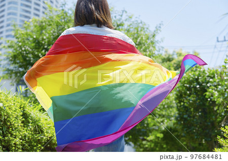 虹色の旗を持った性的マイノリティの女性の後ろ姿 97684481