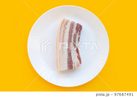 Streaky pork in white plate on yellow background. 97687491