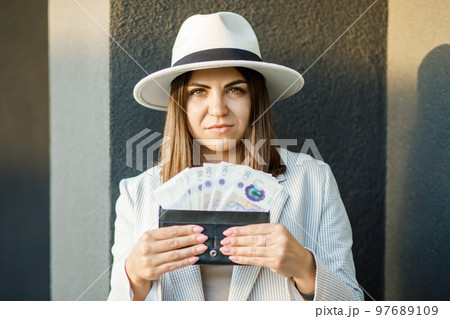 Young business woman holding black wallet with pounds in hands, close up of female hands. The concept of cash payments, savings and salaries 97689109