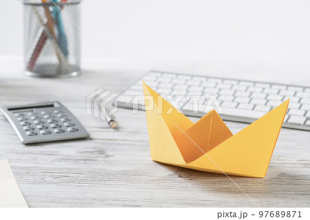 Workspace with office desk and yellow paper ship 97689871