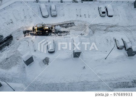 Tractor loader machine uploading dirty snow into dump truck. Tractor loader machine uploading dirty snow into dump truck. 97689933
