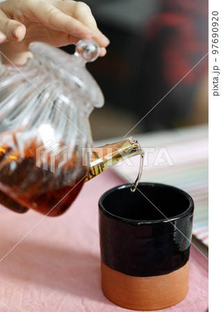 Woman pouring tea into the clay cup 97690920