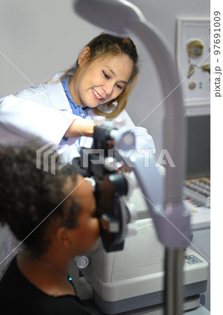 Young woman ophthalmologist checking eye vision of patient for spectacles glasses. Eye health check concept Young woman ophthalmologist checking eye vision of patient for spectacles glasses. Eye health check concept 97691009