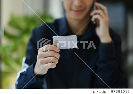 Cropped image of man hand holding a credit card for financial transactions. Finance, loan, savings concept 97691015