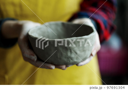 Woman potter's hands holding handmade unbaked ceramic bowl Woman potter's hands holding handmade unbaked ceramic bowl 97691304