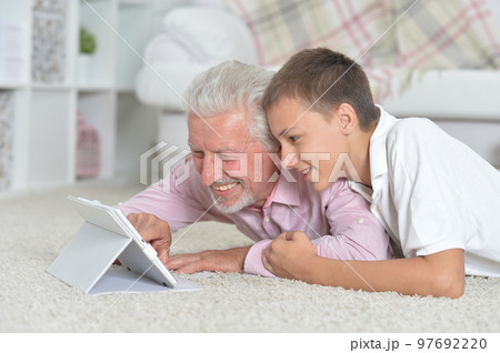 Grandfather with grandson using laptop while lying on floor Grandfather with grandson using laptop while lying on floor 97692220