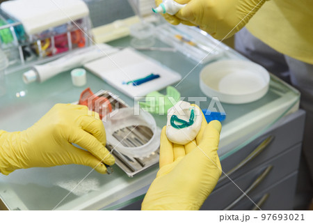 The orthodontist prepares a special paste for making an impression of the patient's teeth 97693021