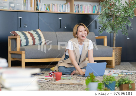 床に書類を広げて仕事をする若い女性 97696181