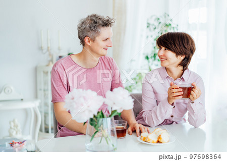 Smiling young man and woman having Breakfast And having fun together at home kitchen with light interior background. Family time. Happy couple in love enjoying each other at their home. 97698364