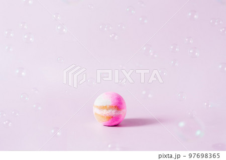 Spa concept. Aromatic Pink bath bomb on the pink background with flying soap bubbles. Selective focus, copy space 97698365