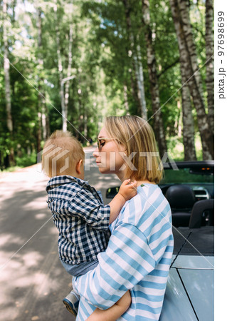 Mom and little son in a convertible car. Summer family road trip to nature 97698699