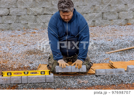 During sidewalk construction project, worker are laying stone concrete paver. During sidewalk construction project, worker are laying stone concrete paver. 97698707