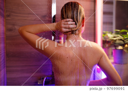 Beautiful woman washes her hair in the shower Beautiful woman washes her hair in the shower 97699091