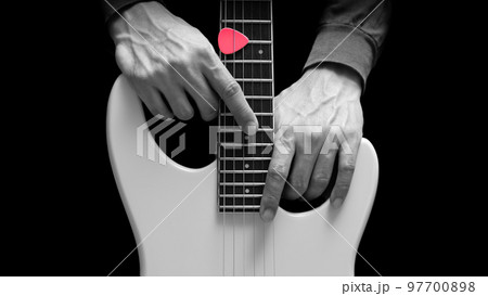 close up musician hands posing on white electric guitar, isolated on black. music background 97700898