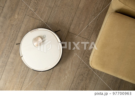 Robotic vacuum cleaner cleans laminated floor near sofa 97700963