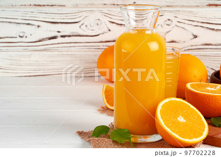Glass of orange juice and cut oranges on table Glass of orange juice and cut oranges on table 97702228