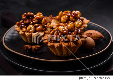 Sweet tasty tart with nuts and honey on a dark concrete background 97702359