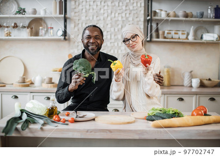 Attractive african american man and muslim young woman cooking dinner together 97702747
