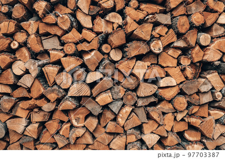 Picturesque wall of firewood logs, rustic background. Wooden pile texture. Chopped dry firewood logs stacked in a rows. Natural alternative heating source. 97703387