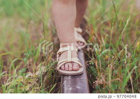 Tiny feet of a child walking the railroad 97704048