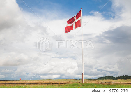 Danish flag on a flagpole against a beautiful cloudy sky Danish flag on a flagpole against a beautiful cloudy sky 97704236