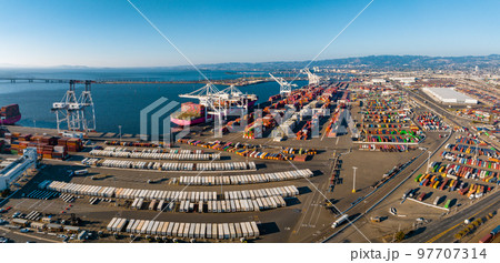 The Oakland Outer Harbor aerial view. Loaded trucks moving by Container cranes. View of busy Port of Oakland. Shipping terminal facility. The Oakland Outer Harbor aerial view. Loaded trucks moving by Container cranes. View of busy Port of Oakland. Shipping terminal facility. 97707314
