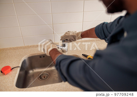 Close up of male plumber repair sink faucet at kitchen. Good quality plumbing company service 97709248