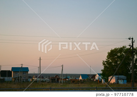 A beautiful rural landscape with houses and power lines against the background of an evening clear sky A beautiful rural landscape with houses and power lines against the background of an evening clear sky 97710778