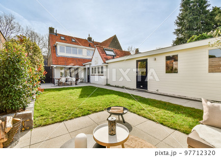 Neat paved patio with sitting area and small garden near wooden fence Neat paved patio with sitting area and small garden near wooden fence 97712320