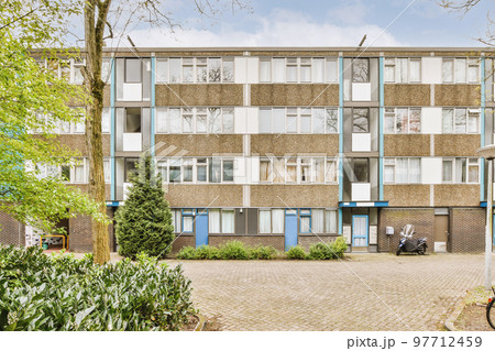 Panorama view of brick houses from an empty sidewalk street with trees and lanterns 97712459