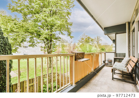 Narrow wooden balcony with wooden railings, wooden chair and door Narrow wooden balcony with wooden railings, wooden chair and door 97712473