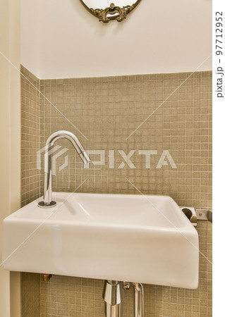 Sink with tap and liquid soap hanging on tiled wall under mirror in contemporary restroom at home 97712952