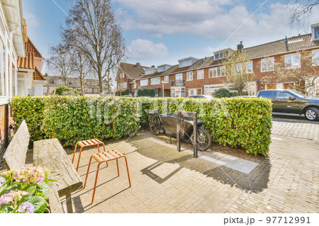 Neat paved patio with sitting area and small garden near wooden fence 97712991