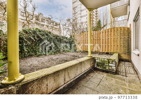 Simple small patio with small garden near wooden fence Simple small patio with small garden near wooden fence 97713338
