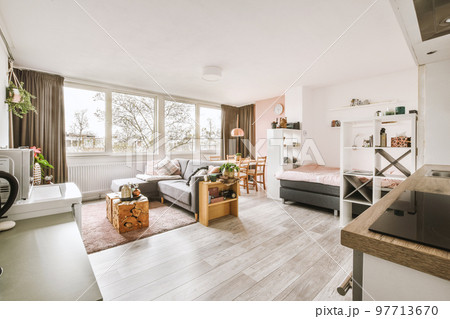 Table with chairs and flowers located near lounge area and kitchen in spacious room of contemporary apartment Table with chairs and flowers located near lounge area and kitchen in spacious room of contemporary apartment 97713670