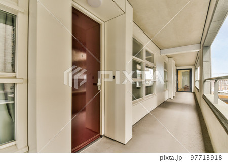 Corridor of contemporary apartment with black closets and opened doorway leading to terrace 97713918