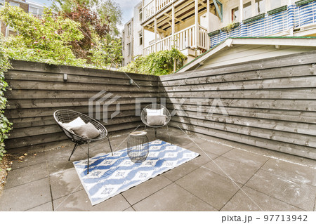 Neat paved patio with sitting area and small garden near wooden fence Neat paved patio with sitting area and small garden near wooden fence 97713942
