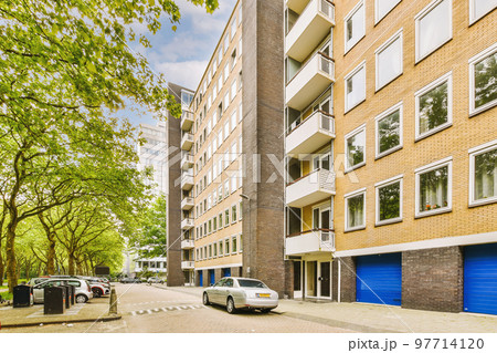 Panorama view of brick houses from an empty sidewalk street with cars, trees and lanterns 97714120