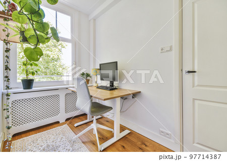 Comfortable chair placed near desk with computer monitors and whiteboard in light workplace in modern apartment 97714387